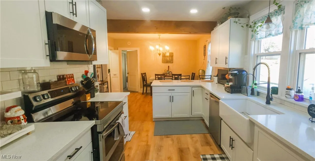 Kitchen with modern appliances and white cabinetry, open to dining area. A great place to entertain guest.