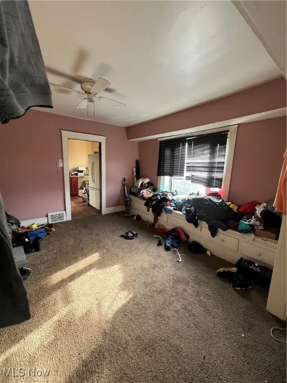 Bedroom featuring dark colored carpet, fridge, and ceiling fan