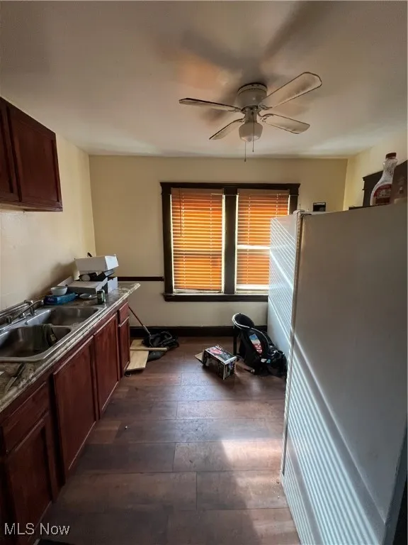 Kitchen with ceiling fan, fridge, dark wood-type flooring, and sink