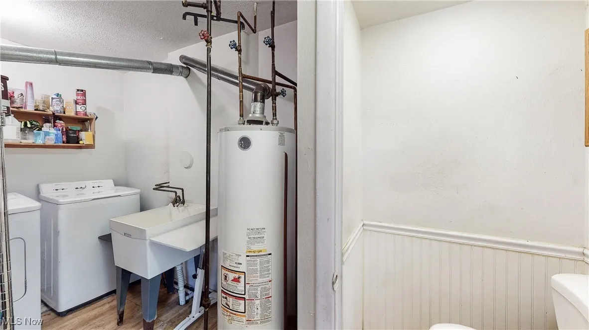 Laundry room with light hardwood / wood-style floors, washing machine and clothes dryer, and water heater