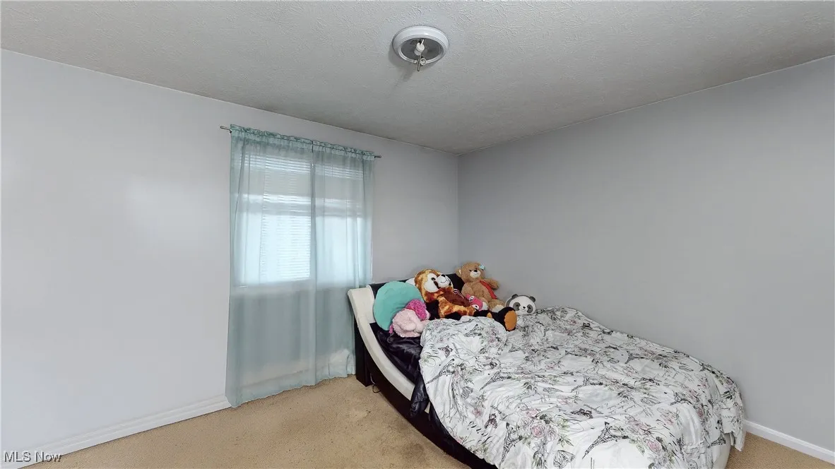 Bedroom featuring light carpet and a textured ceiling