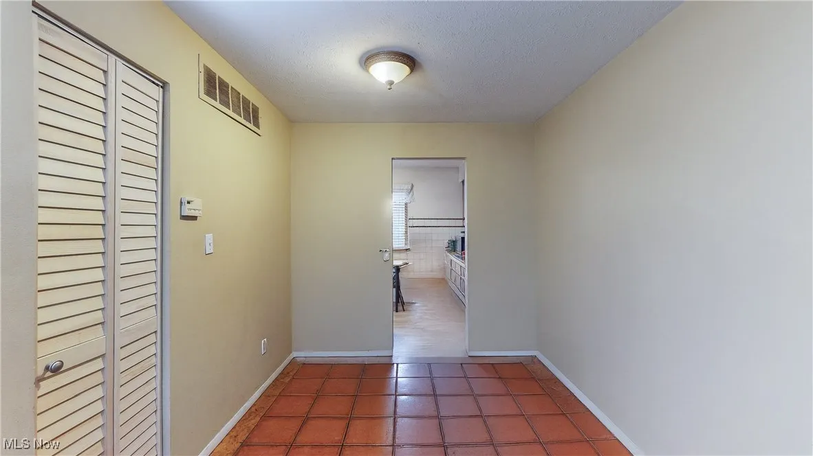 Hallway featuring a textured ceiling and tile patterned floors