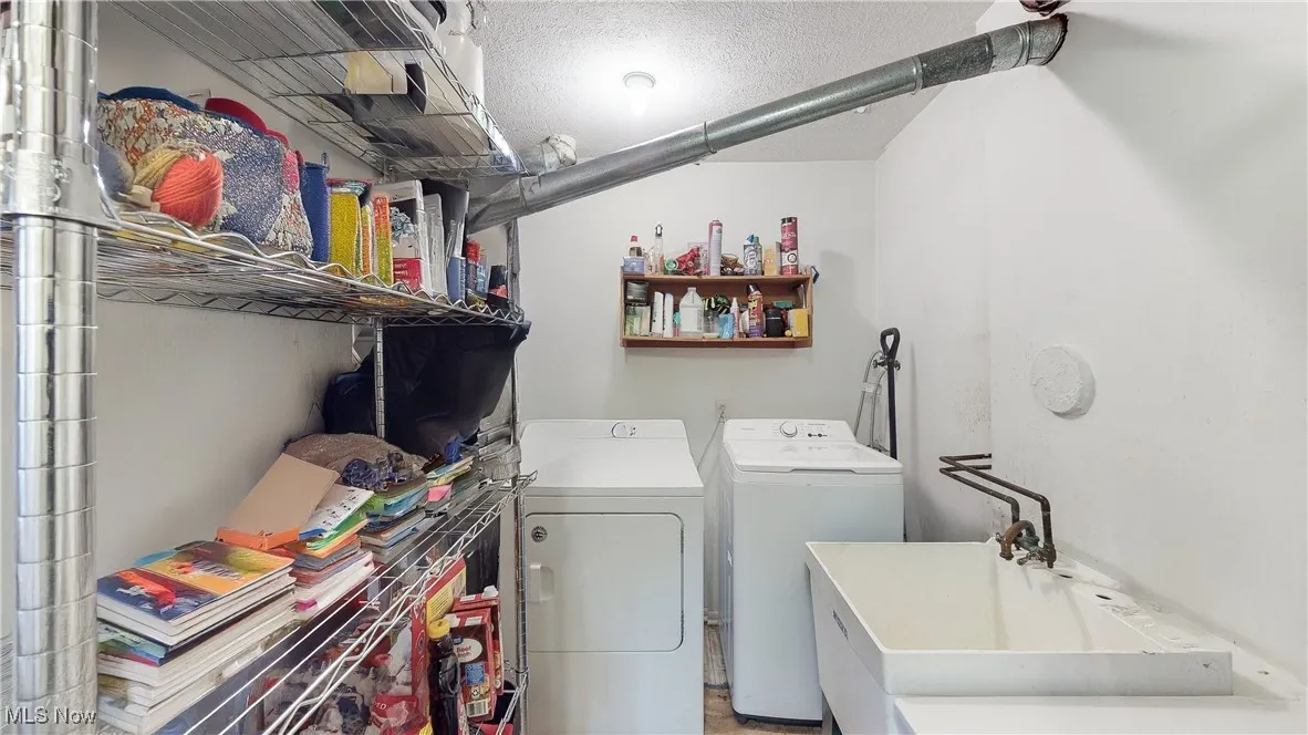 Washroom featuring independent washer and dryer, a textured ceiling, and sink