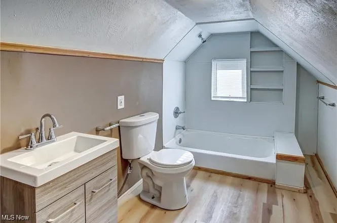 Bathroom with lofted ceiling, wood-type flooring, a textured ceiling, and vanity