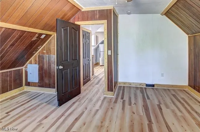 Additional living space featuring wooden walls, wood ceiling, vaulted ceiling, and light wood-type flooring
