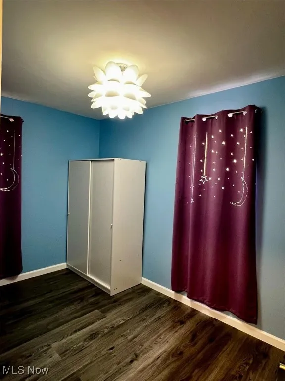 Unfurnished bedroom featuring a closet, dark wood-type flooring, and a chandelier