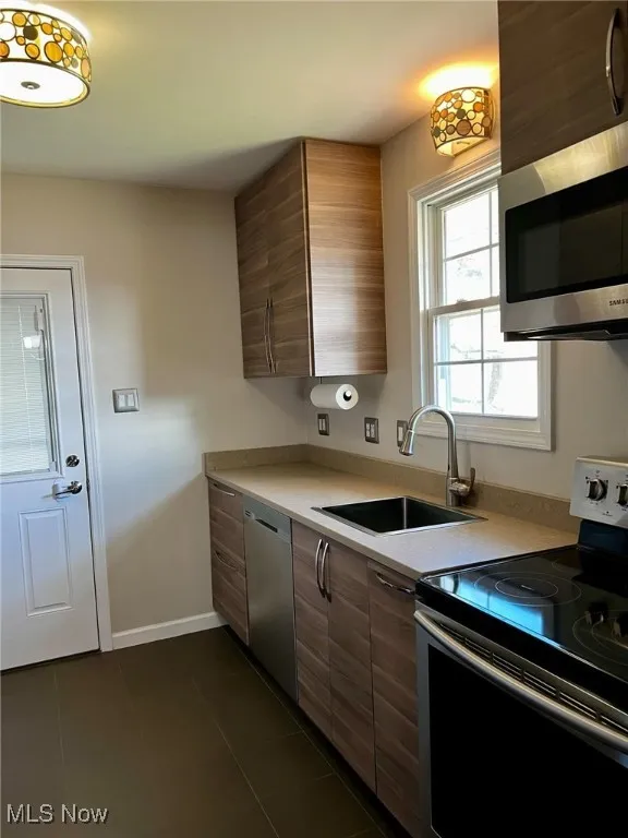Kitchen featuring sink, dark tile patterned flooring, and appliances with stainless steel finishes