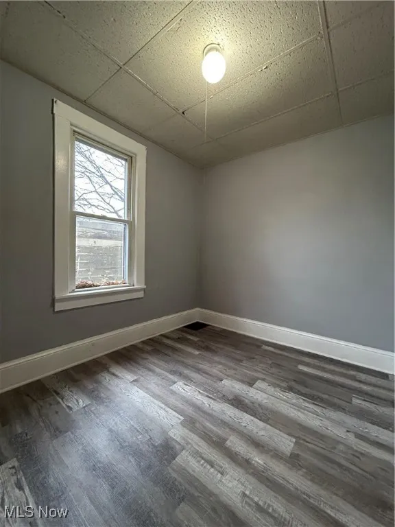 Empty room featuring a drop ceiling and wood-type flooring