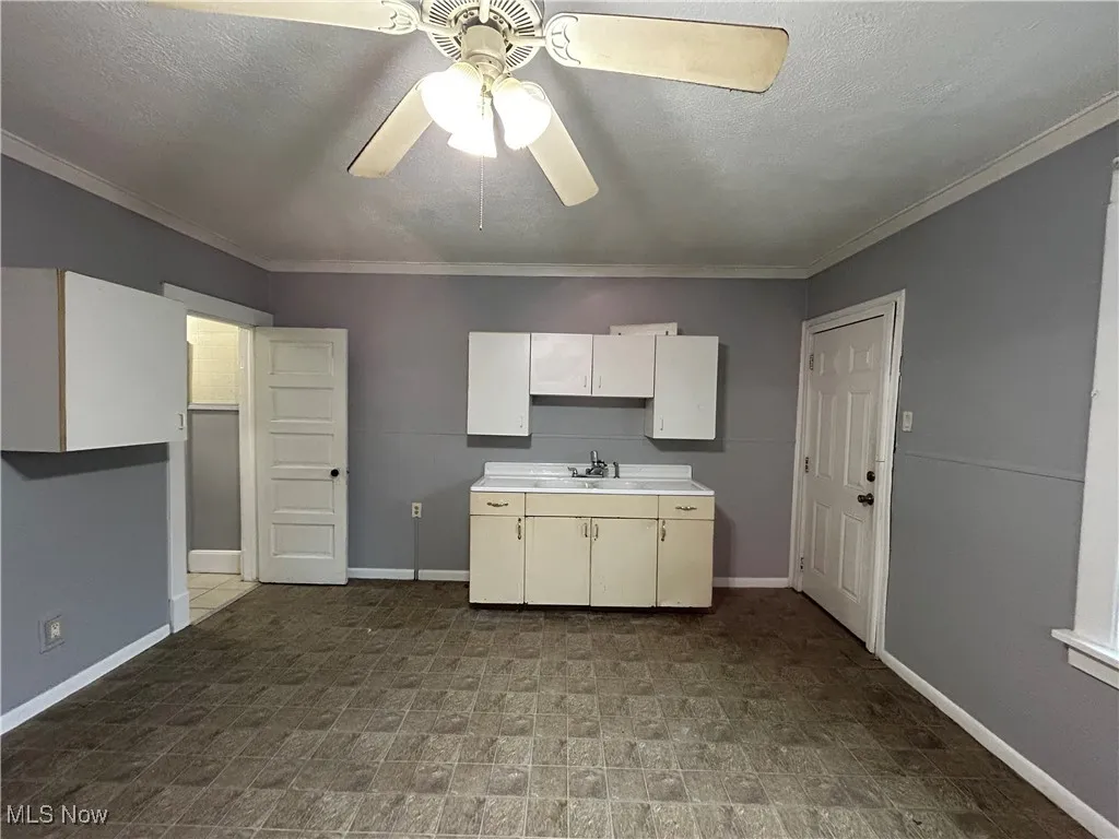 Kitchen featuring ceiling fan, ornamental molding, and sink