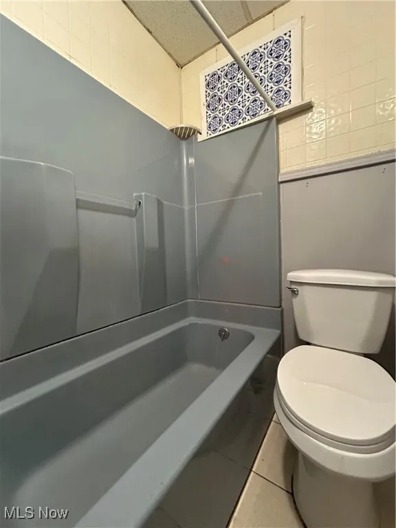 Bathroom featuring tile patterned flooring, toilet, and shower / bath combination