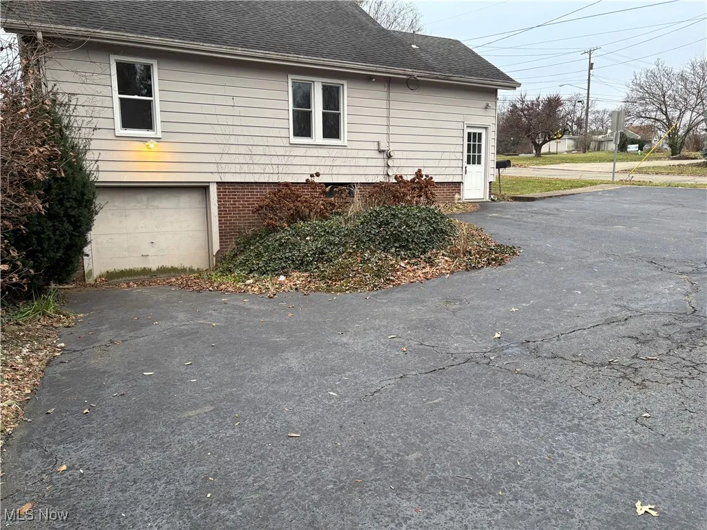 Back of property paved parking out with ample parking space and garage door access to basement.