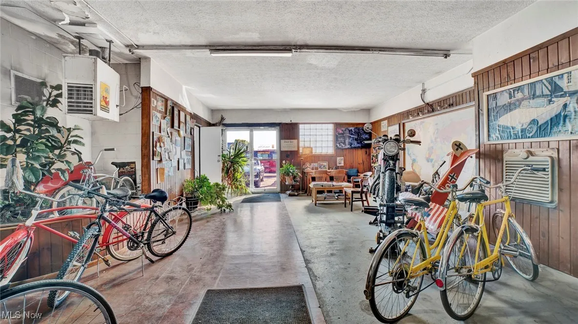 Misc room featuring concrete flooring, a textured ceiling, and wooden walls