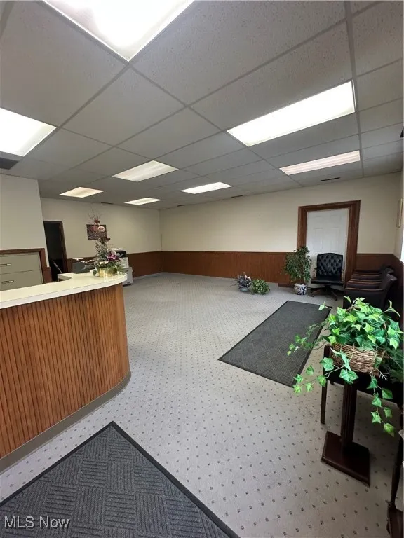 Welcome area with a drop ceiling, a wainscoted wall, and wooden walls