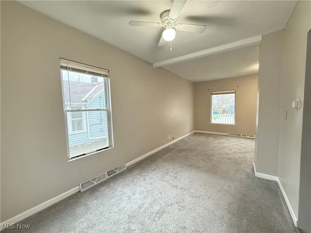 Carpeted spare room featuring baseboards, ceiling fan, and visible vents