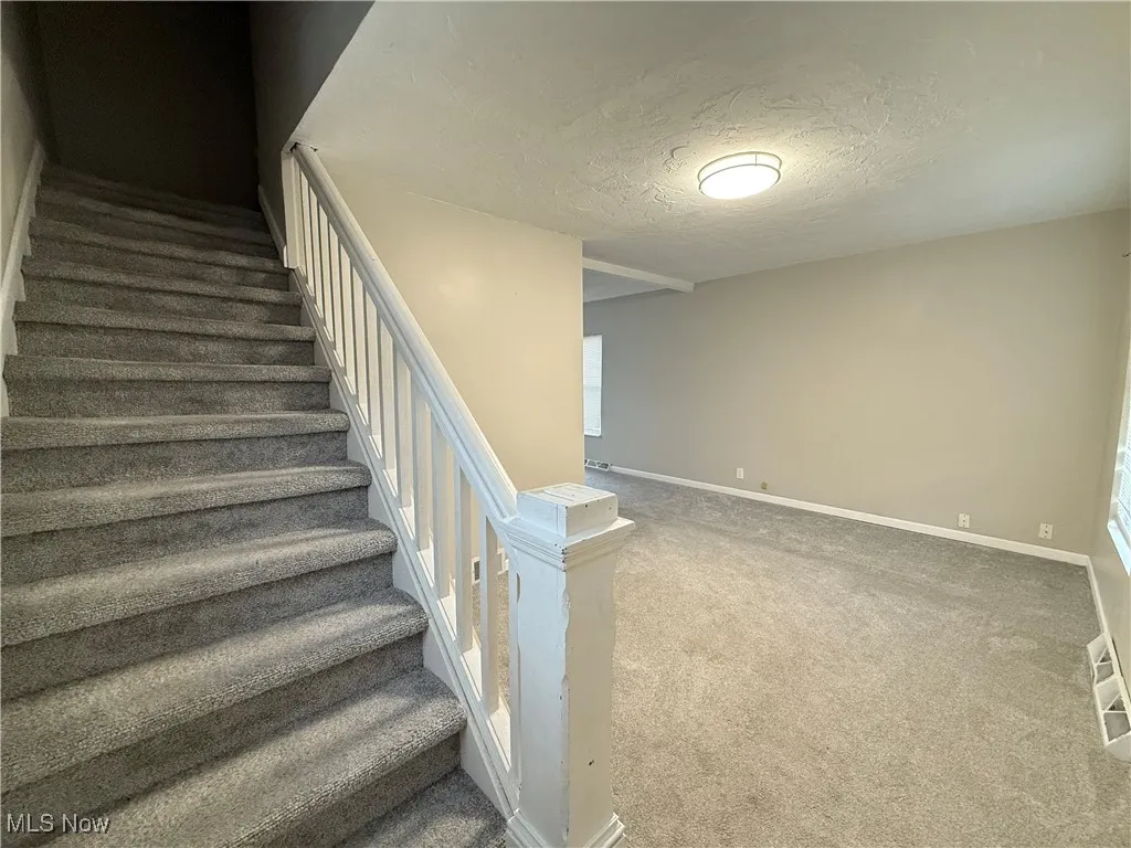 Staircase with baseboards, a textured ceiling, and carpet