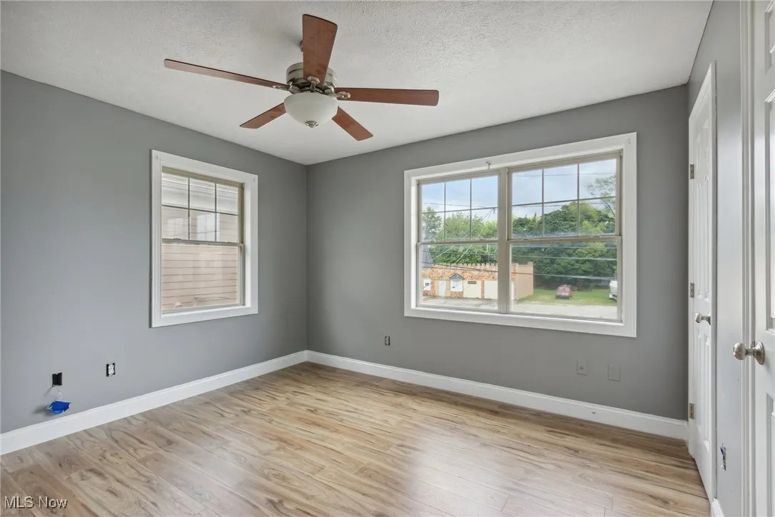 Unfurnished room with ceiling fan, light wood-type flooring, and a textured ceiling