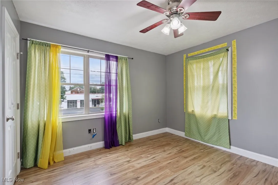 Empty room with ceiling fan and light wood-type flooring