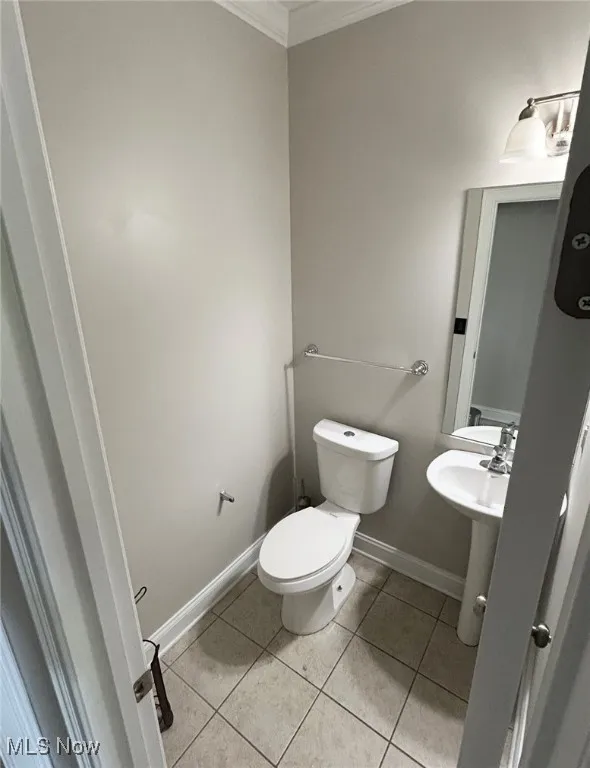 Bathroom featuring crown molding, toilet, tile patterned floors, and baseboards