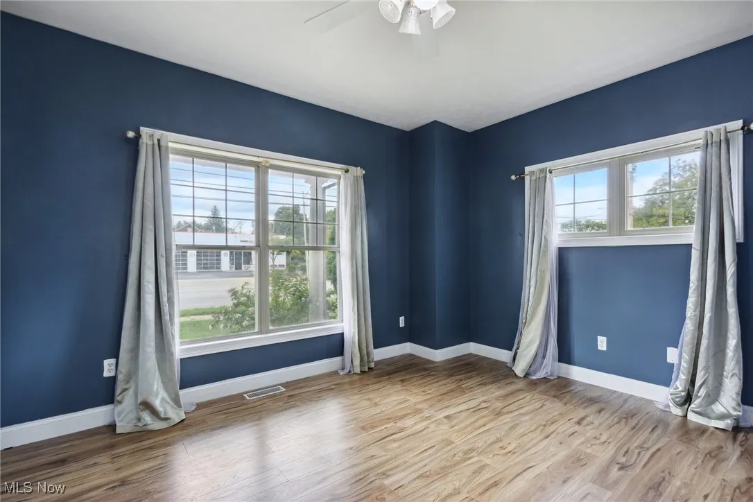 Empty room with ceiling fan, plenty of natural light, and light hardwood / wood-style flooring