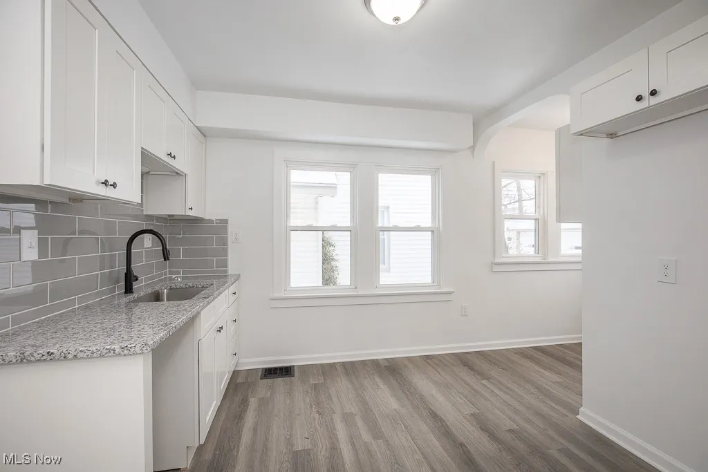 Kitchen featuring white cabinets, tasteful backsplash, light hardwood / wood-style flooring, and sink
