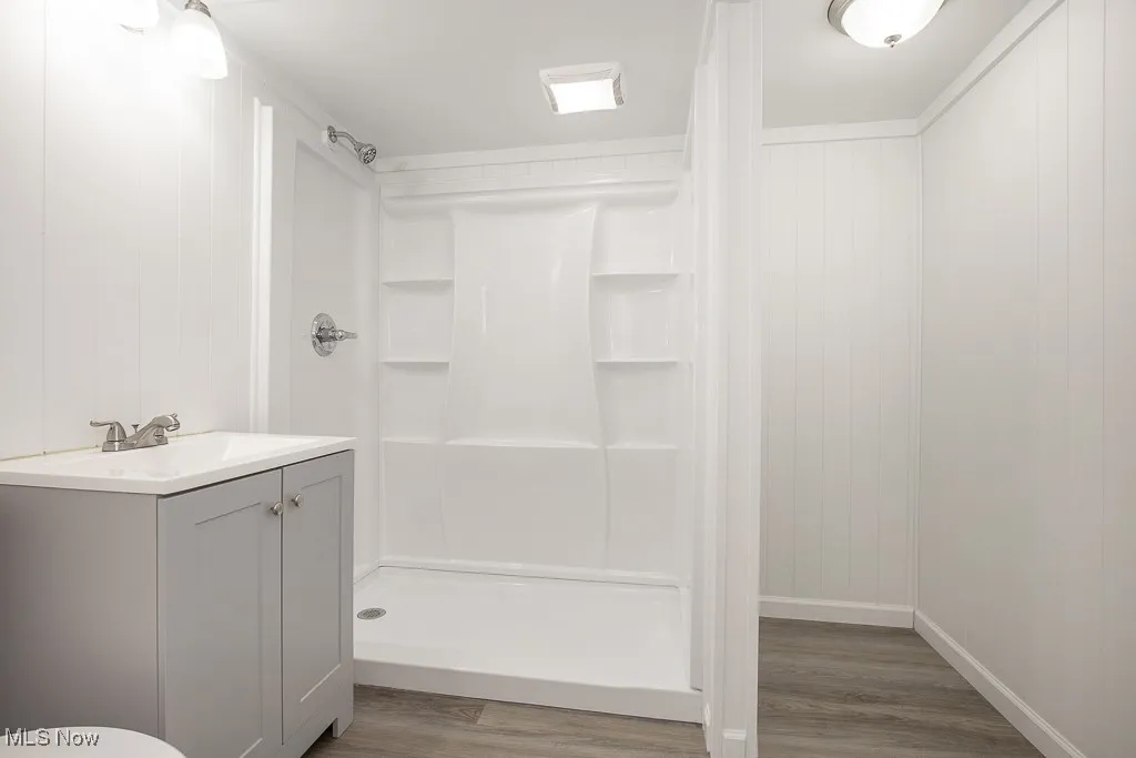 Bathroom with a shower, vanity, and wood-type flooring