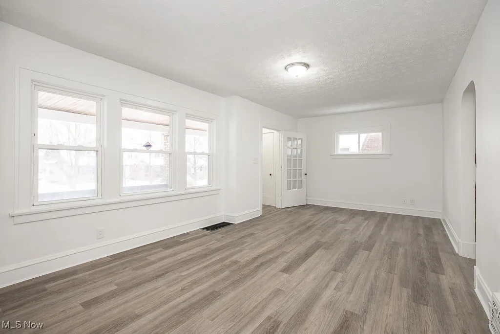 Empty room featuring a textured ceiling and dark hardwood / wood-style floors