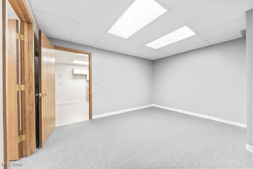 Carpeted empty room with a paneled ceiling and baseboards