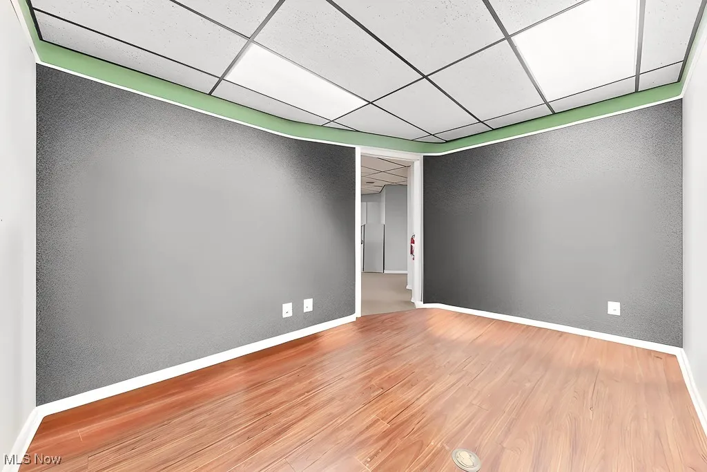 Spare room featuring a paneled ceiling, baseboards, and wood finished floors