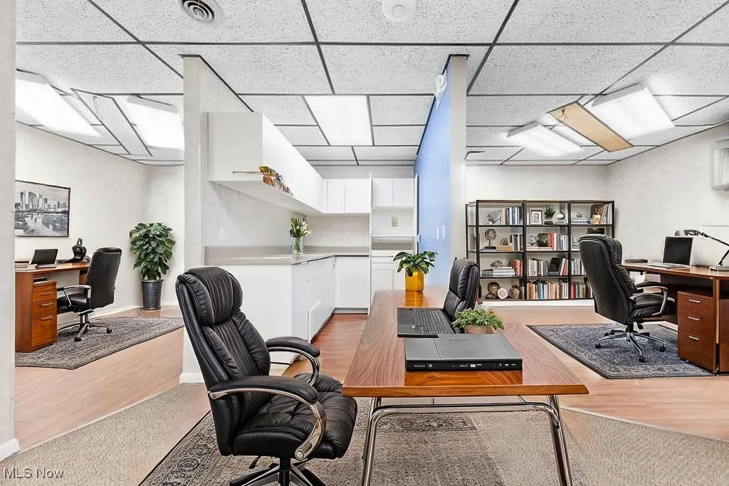 Office space with a drop ceiling, visible vents, and wood finished floors