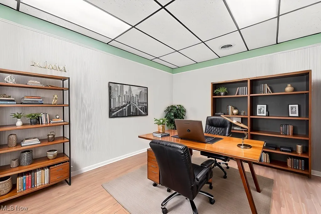 Office area featuring visible vents, baseboards, light wood-style flooring, and a paneled ceiling