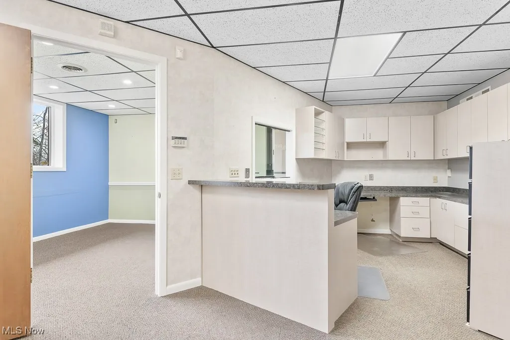 Kitchen with freestanding refrigerator, light colored carpet, recessed lighting, a drop ceiling, and baseboards