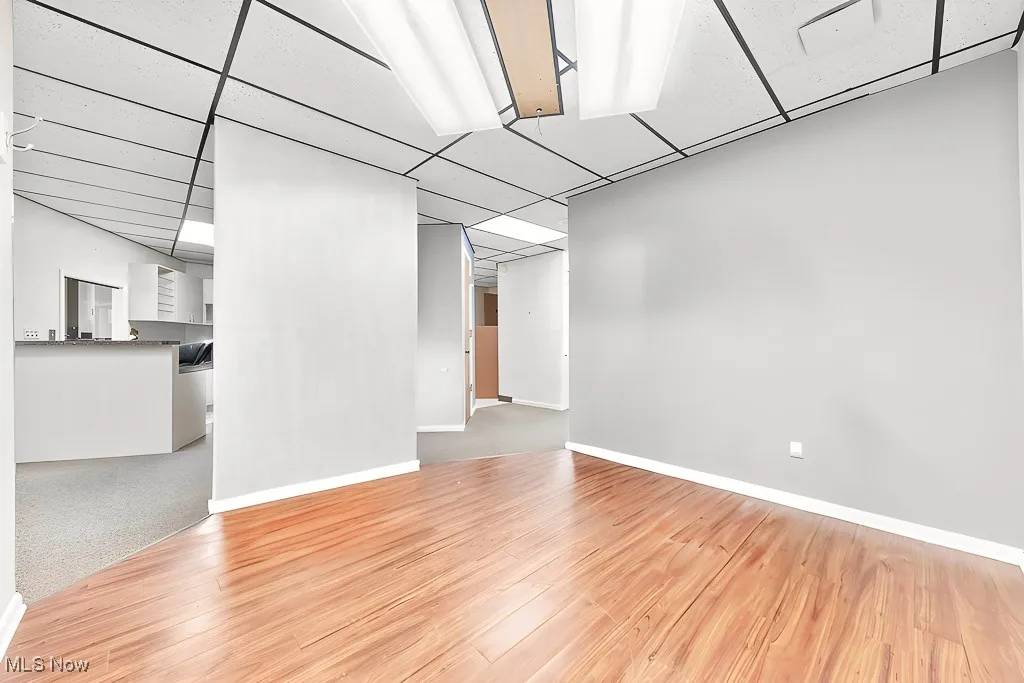 Below grade area featuring a paneled ceiling, baseboards, and wood finished floors