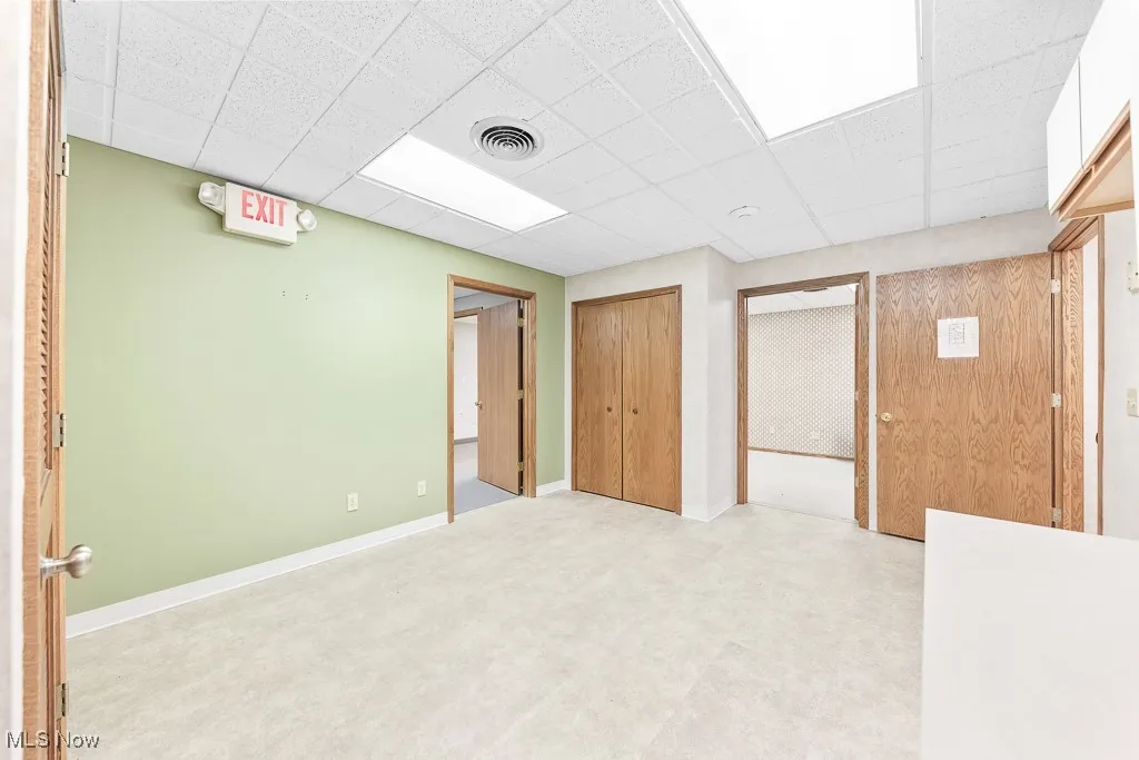 Below grade area with a drop ceiling, visible vents, and baseboards