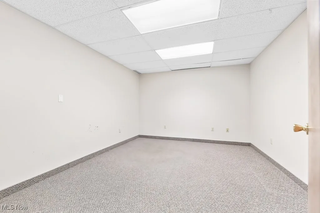 Carpeted empty room with baseboards and a paneled ceiling