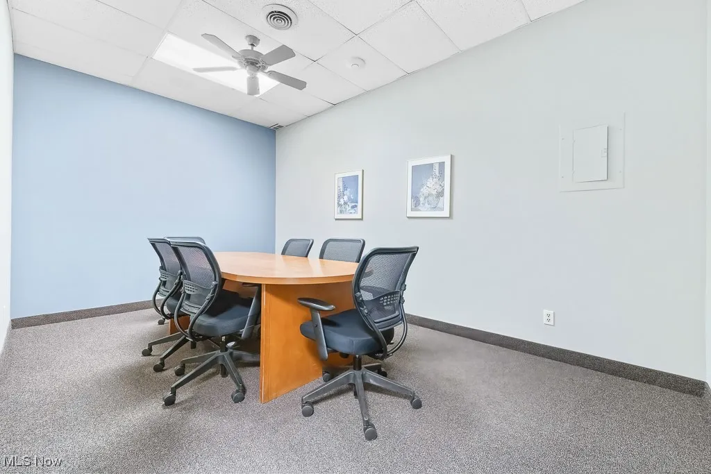 Carpeted office with baseboards, a drop ceiling, visible vents, and ceiling fan