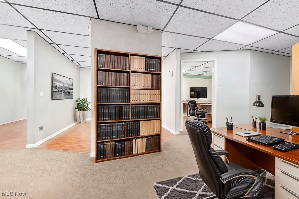 Office area featuring a drop ceiling, baseboards, and carpet floors