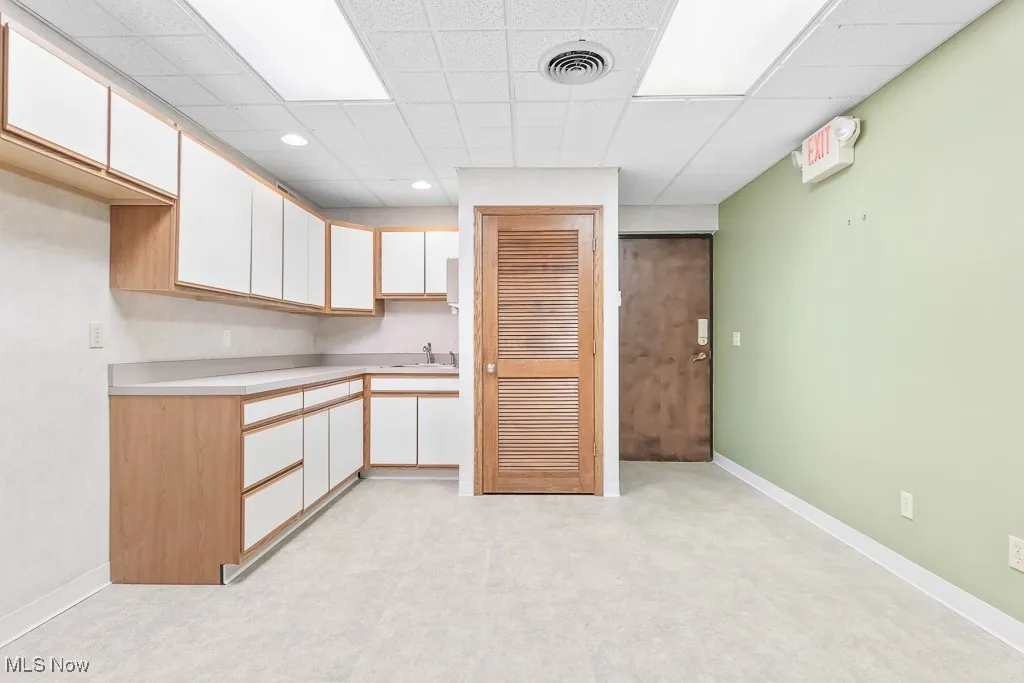 Kitchen featuring a sink, white cabinetry, light countertops, and visible vents