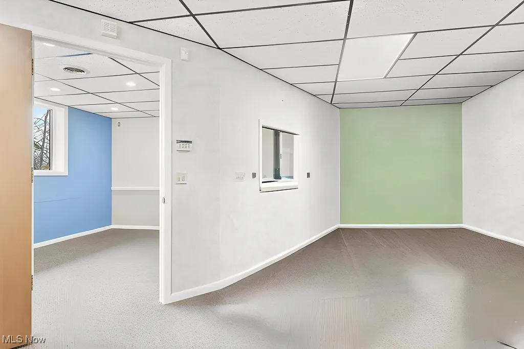 Empty room featuring a paneled ceiling, baseboards, and recessed lighting