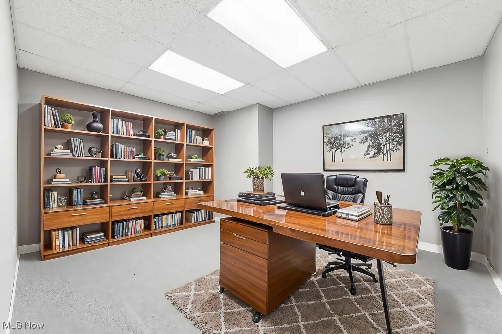 Office area with baseboards, a drop ceiling, and finished concrete floors