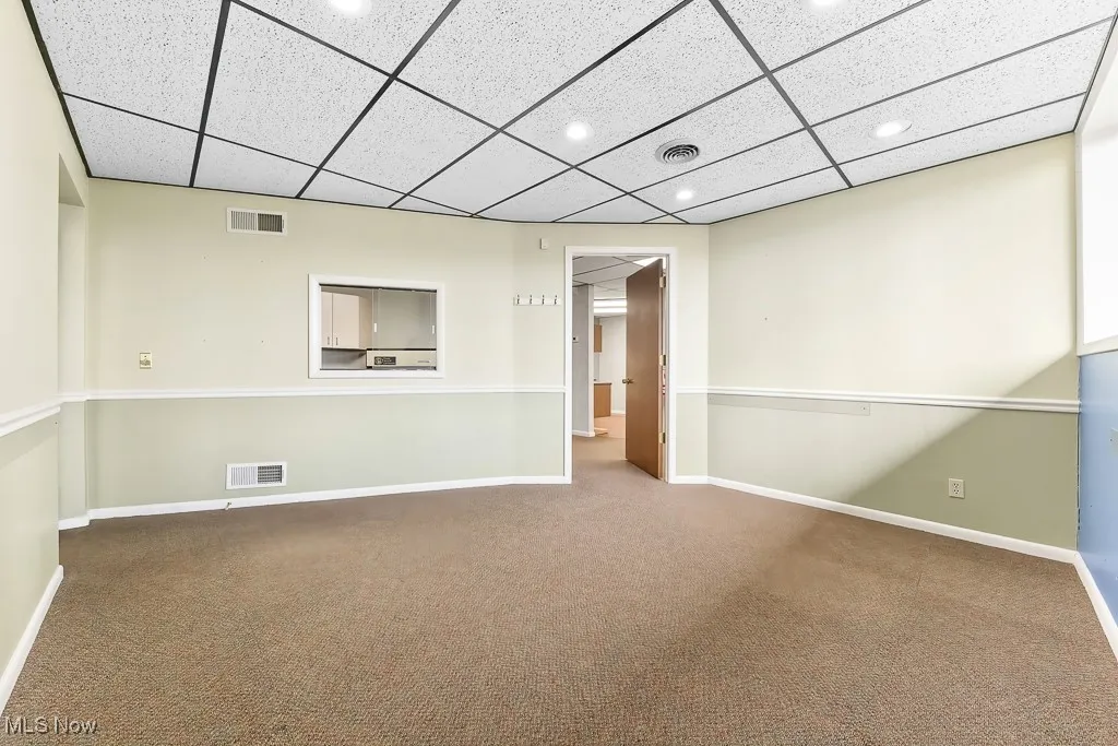 Carpeted spare room featuring a paneled ceiling, visible vents, and recessed lighting