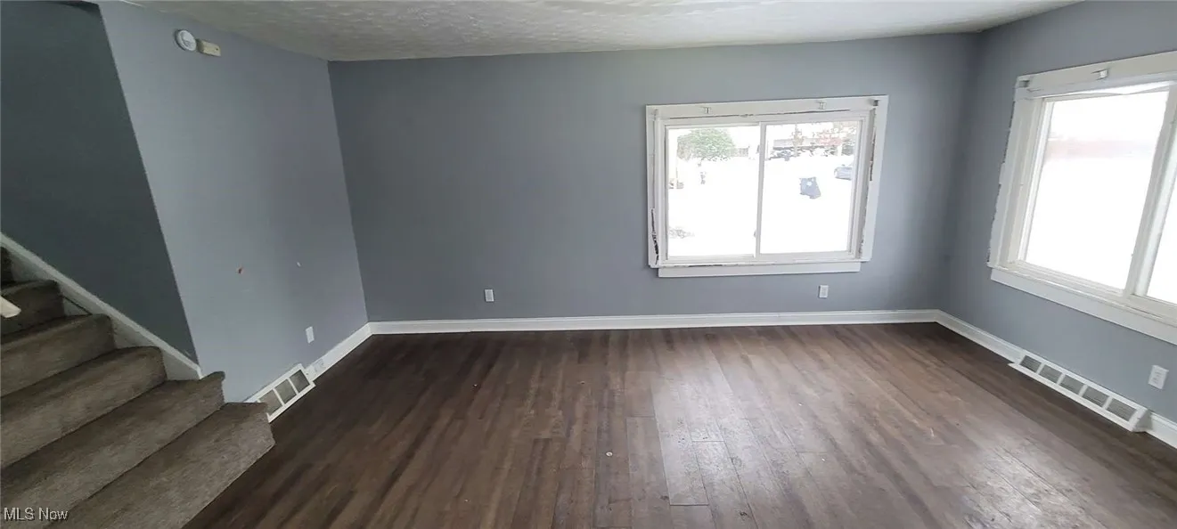 Empty room featuring a textured ceiling and dark wood-type flooring