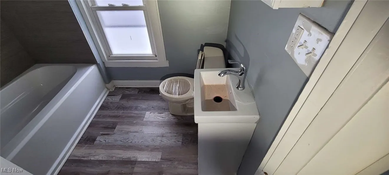 Bathroom featuring hardwood / wood-style flooring, vanity, toilet, and a bath