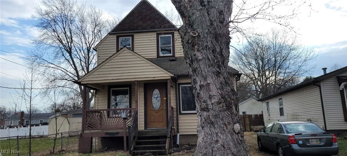 View of front of house with fence, covered porch, and roof with shingles