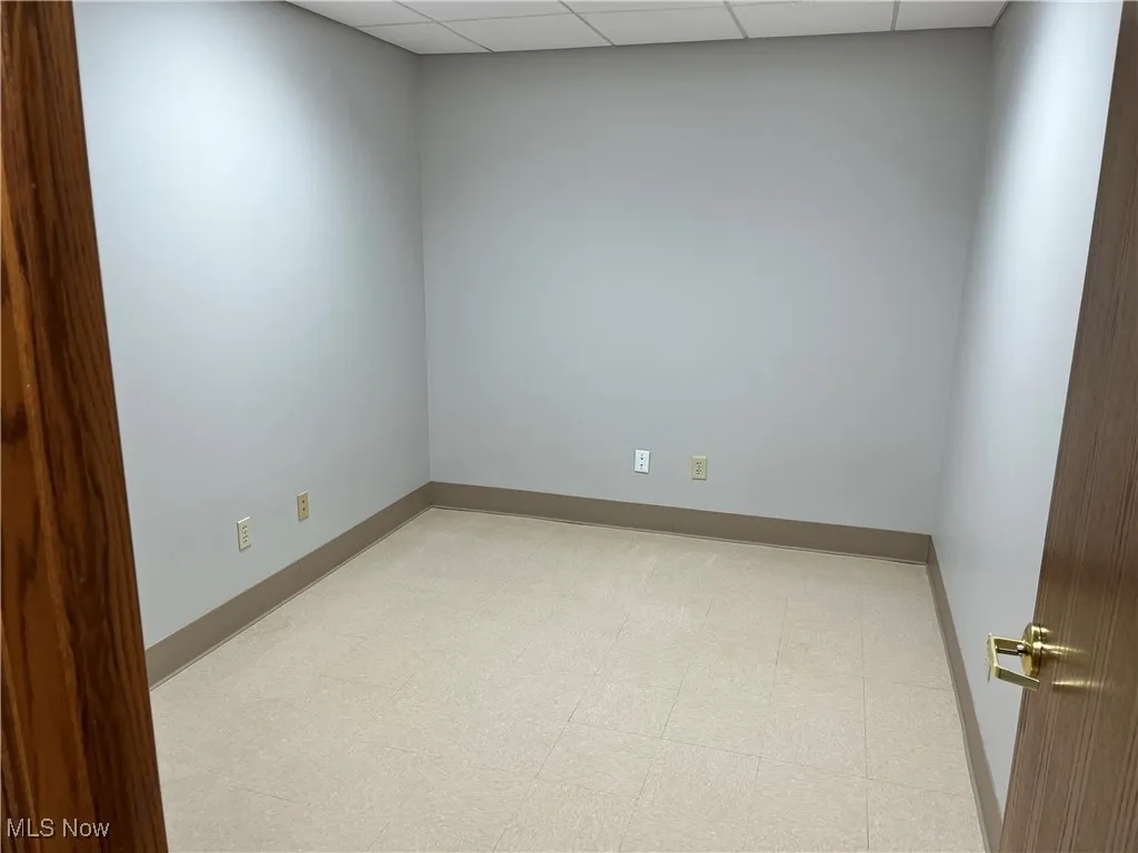 Unfurnished room featuring a paneled ceiling and baseboards