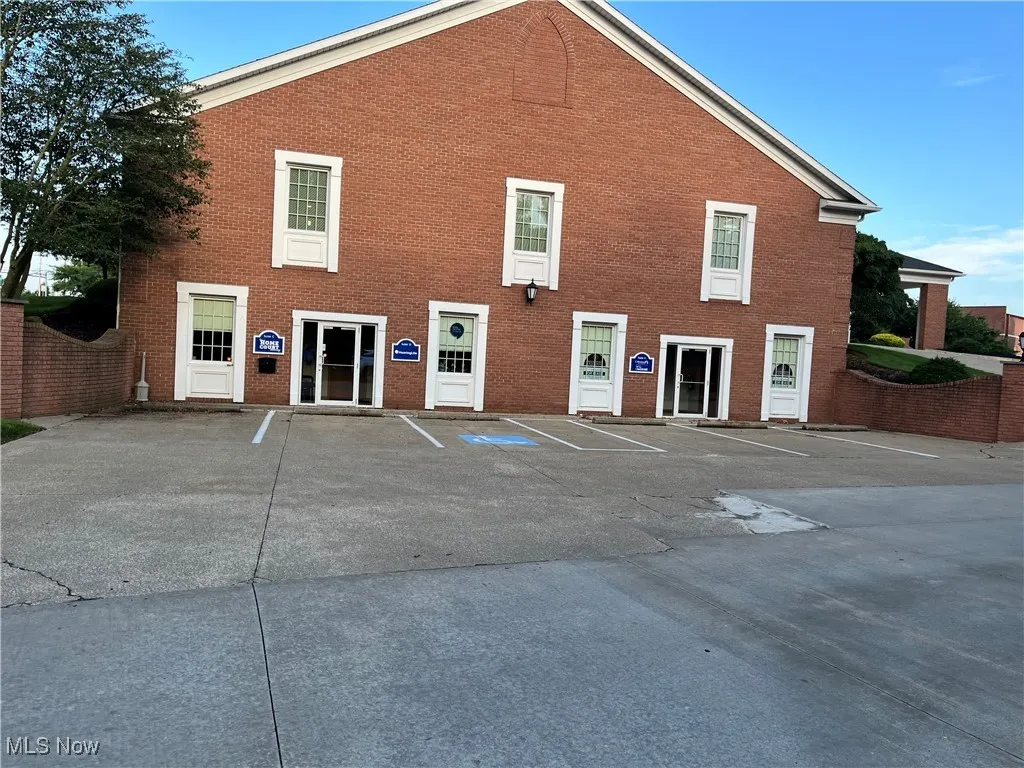 View of front facade featuring uncovered parking and brick siding