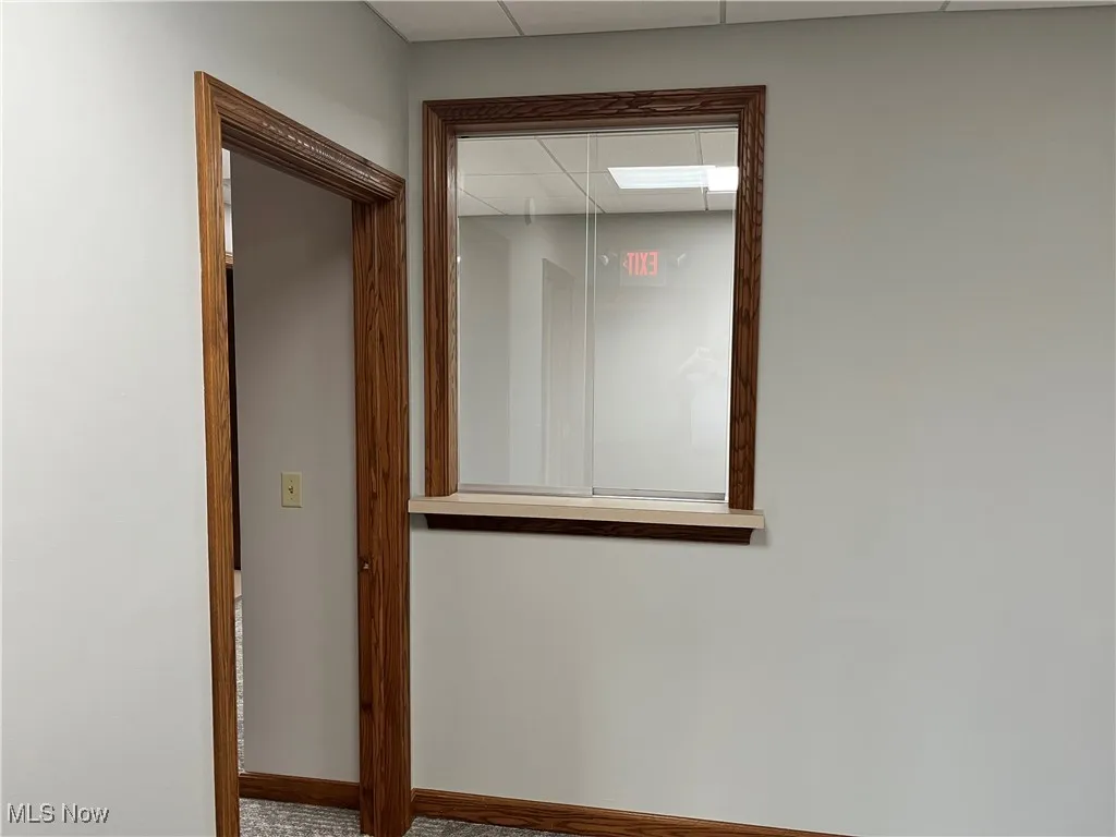 Corridor featuring a drop ceiling and baseboards