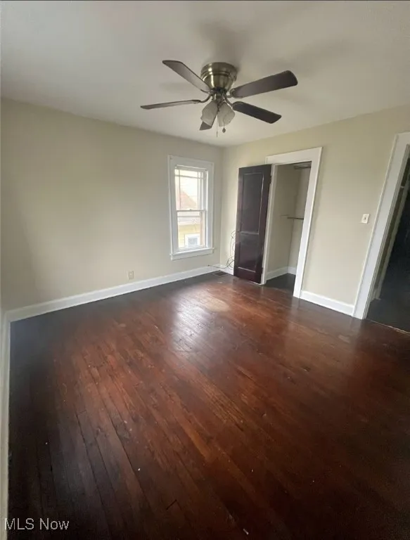 Unfurnished bedroom with dark hardwood / wood-style flooring, a closet, and ceiling fan