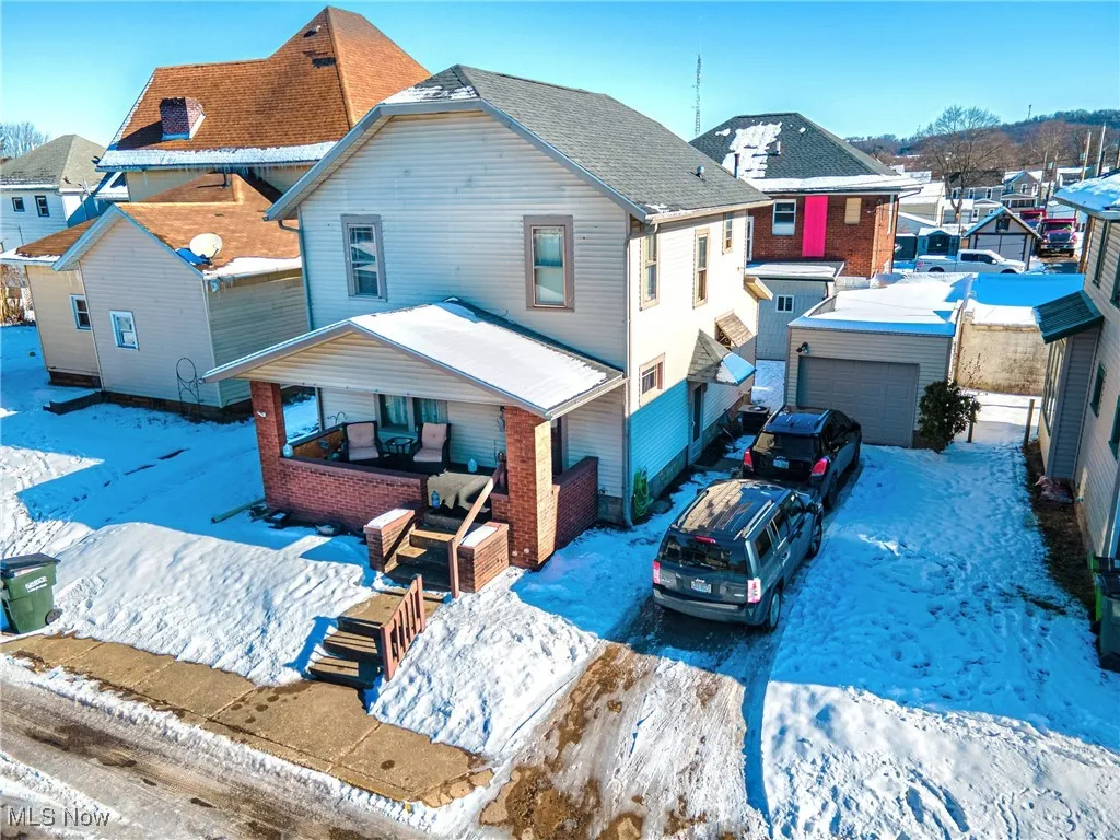 Snow covered rear of property with covered porch