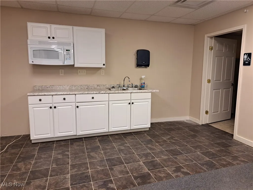 Kitchenette featuring sink and white cabinets and microwave