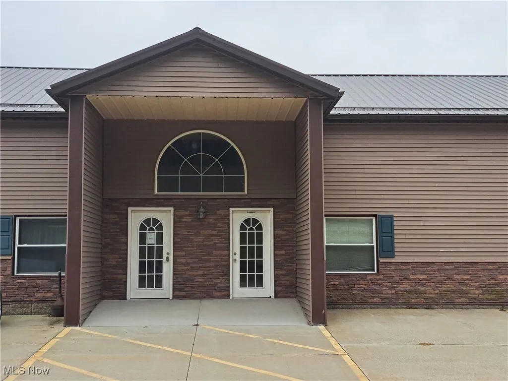 Property entrance with stone siding and a metal roof